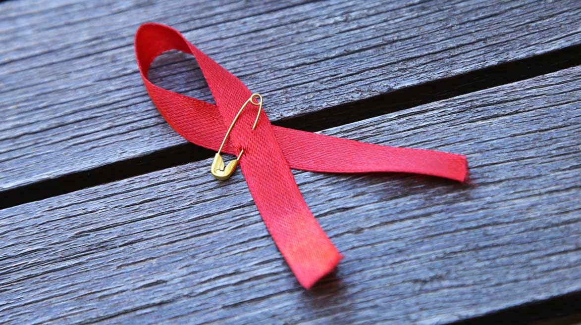 Pequeno laço vermelho representando a campanha sobre o câncer de mama.