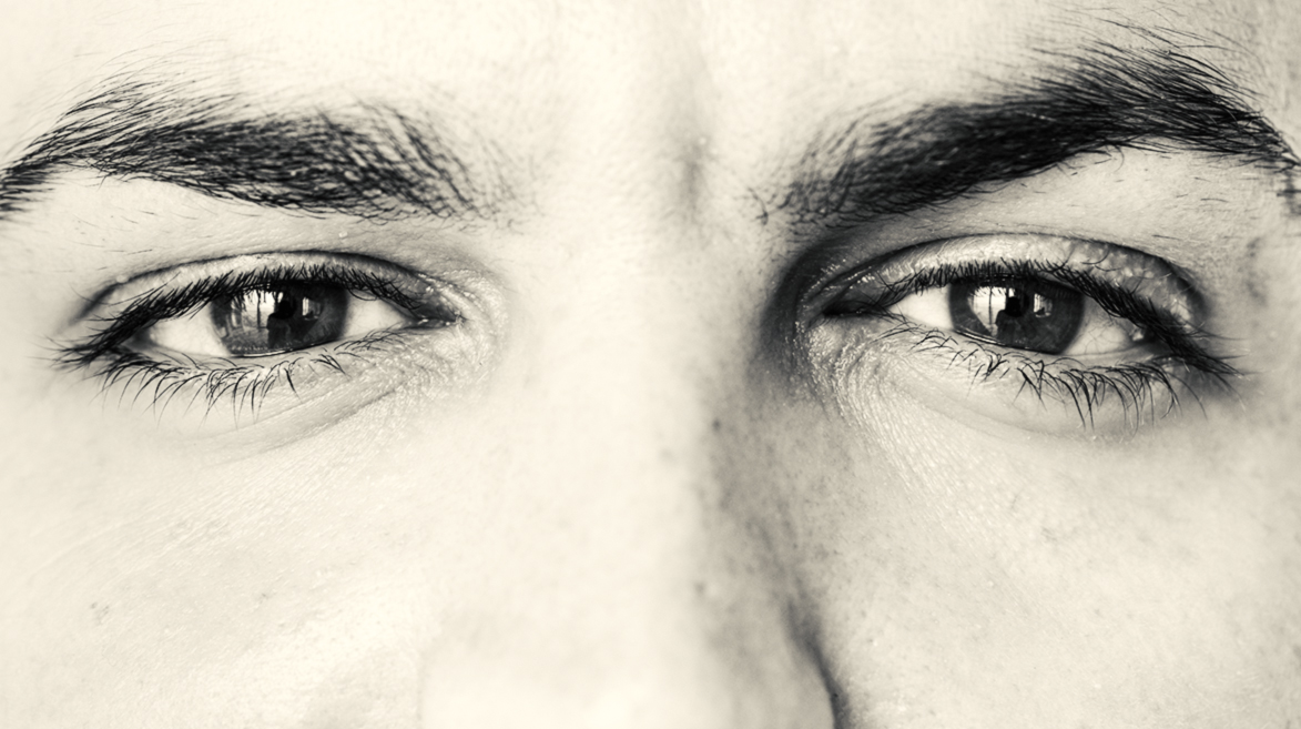 Close-up em olhos masculinos com expressão reflexiva. 