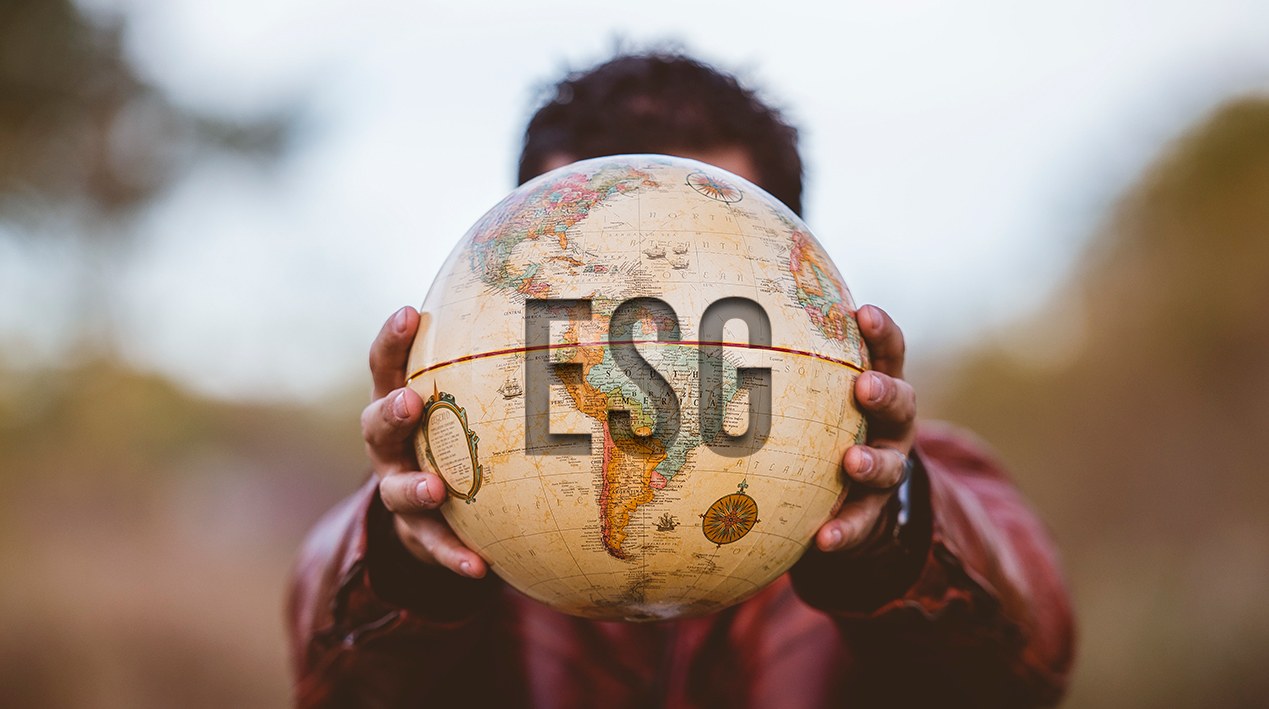 Homem segurando a frente da cabeça um globo terrestre com a sigla ESG.