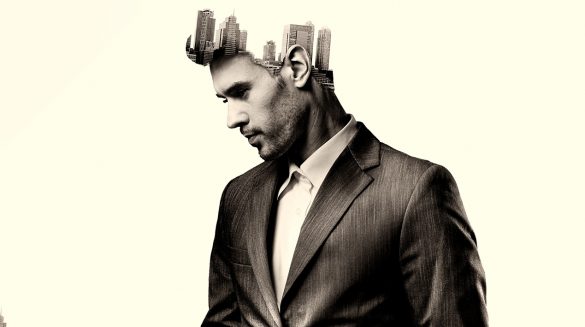 Fotomontagem de um homem de perfil usando um terno e edifícios crescendo a partir de sua cabeça